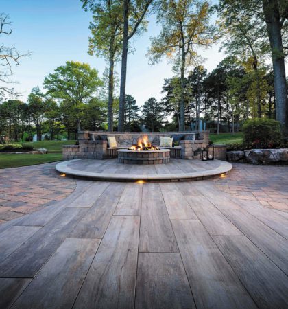 Fire pit on a paver patio with warm accent lighting in a Charlotte, NC backyard