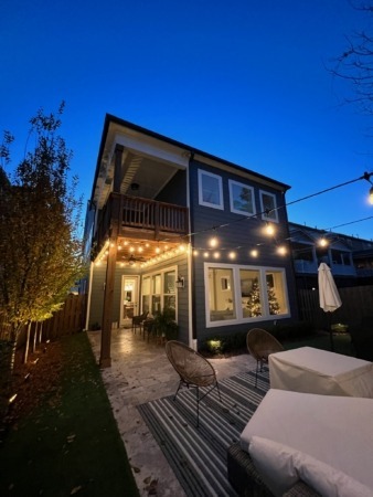 Backyard patio lit with bistro string lights and landscape uplighting at dusk in Charlotte, NC