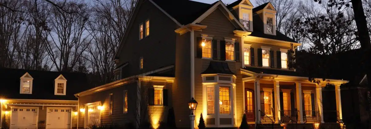 Charlotte Lighting & Hardscapes offers affordable solutions in the Charlotte Metro area. Landscape lighting, Hardscapes and Artificial Turf solutions, a house with lights on the front, outdoor lighting trends