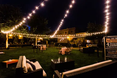 Warm bistro string lights hanging over a backyard patio seating area at dusk in Charlotte, NC