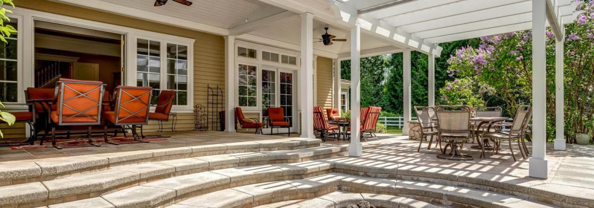Paver patio with integrated landscape lighting and a seating wall at dusk in Charlotte, NC